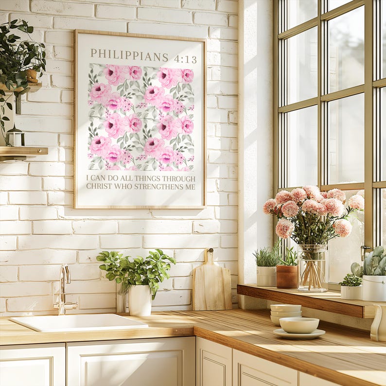 May include: A framed print with a floral pattern of pink roses and green foliage. The print displays the text "PHILIPPIANS 4:13" and "I CAN DO ALL THINGS THROUGH CHRIST WHO STRENGTHENS ME". It is mounted on a white brick wall.