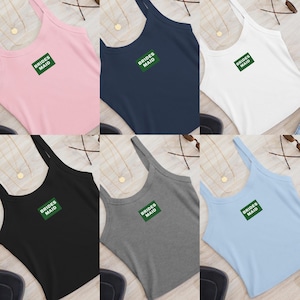 K&ouml;nnte beinhalten: Sechs Tanktops in verschiedenen Farben: Rosa, Marineblau, Wei&szlig;, Schwarz, Grau und Hellblau. Jedes Oberteil hat den gr&uuml;nen Schriftzug "BRIDES MAID" auf einem gr&uuml;nen Rechteck.
