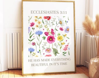 May include: A framed print featuring a watercolor floral arrangement with various flowers in shades of pink, blue, yellow, and white. The text "Ecclesiastes 3:11" and "He has made everything beautiful in its time" are printed on the white background.