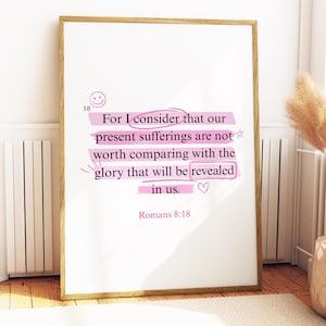 May include: A framed print with a white background and gold frame. The print features text from Romans 8:18, highlighted in pink, with a smiley face and heart icon. The text reads, "For I consider that our present sufferings are not worth comparing with the glory that will be revealed in us."