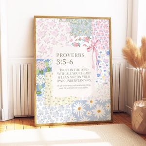 Può includere: Una stampa incorniciata con un design patchwork con motivi floreali rosa, blu e bianchi. Il testo "PROVERBI 3:5-6" è visualizzato, insieme a una citazione sulla fiducia nel Signore. Un nastro rosa aggiunge un tocco decorativo.