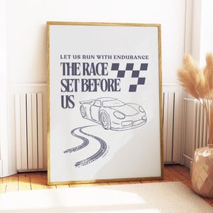 May include: A framed print with a gold-colored frame. The print features a car illustration, tire tracks, and text that reads "LET US RUN WITH ENDURANCE THE RACE SET BEFORE US". A checkered flag design is also included.