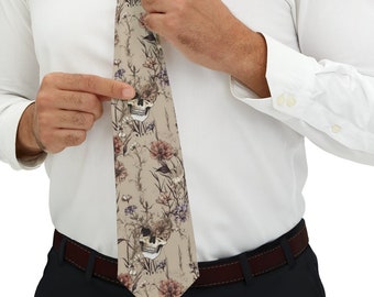 May include: A beige necktie featuring a repeating pattern of human skulls interspersed with various wildflowers in muted tones of brown, red, and blue. The tie is worn with a crisp white long-sleeved button-down shirt and dark trousers.