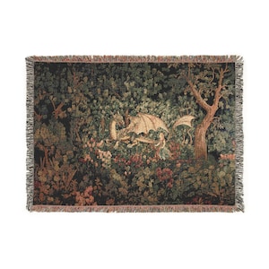 May include: A woven tapestry throw blanket featuring a fantasy scene with a dragon, a person, and lush foliage. The color palette includes greens, browns, and touches of red. The blanket has a fringed edge.
