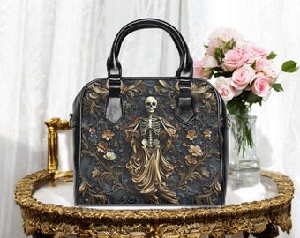 Può includere: Borsa nera con un design a scheletro. La borsa presenta un manico nero e un motivo floreale con una figura di scheletro al centro. La borsa è su un tavolo dorato con un vaso di rose rosa sullo sfondo.