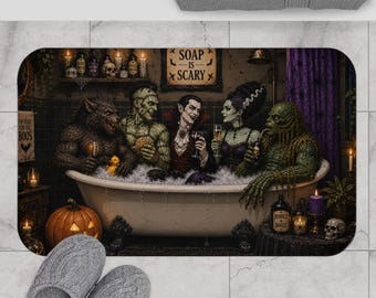 May include: A rectangular bath mat featuring a graphic illustration of classic horror movie monsters in a bathtub. The scene includes a werewolf, Frankenstein's monster, a vampire, the Bride of Frankenstein, and a swamp creature. Text reads SOAP IS SCARY.