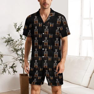 Könnte beinhalten: Schwarzes Pyjama-Set mit einem sich wiederholenden Muster aus Whiskyflaschen und Gläsern. Das kurzärmelige Hemd und die Shorts sind aus weichem Material. Das Set hat ein Hemd mit Knöpfen und einem Reverskragen.