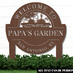 K&ouml;nnte beinhalten: Ein braunes Garten Schild aus Metall mit dem Text "Willkommen im Garten von Papa San Antonio, TX". Das Schild zeigt einen Korb mit Gem&uuml;se und der Text kann personalisiert werden.