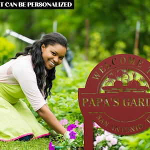 K&ouml;nnte beinhalten: Rotes Metall-Gartenschild mit dem Text "Willkommen im Garten von Papa San Antonio TX". Das Schild zeigt einen Korb mit Gem&uuml;se und ist in einem Garten aufgestellt.