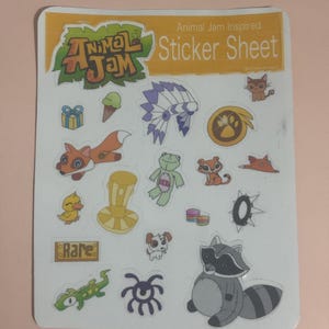 Peut inclure: Une planche d'autocollants avec divers motifs inspirés d'Animal Jam. La feuille présente un logo, le texte "Sticker Sheet" et plusieurs autocollants d'animaux et d'objets, dont un renard, un raton laveur et une coiffe amérindienne.