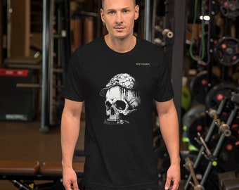 May include: A black short-sleeved t-shirt featuring a graphic of a skull wearing a hat covered in mushrooms. The word MYSTERY is printed in small gold letters above the graphic. The shirt has a crew neckline and a standard fit design.