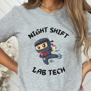 May include: Gray t-shirt with a cartoon ninja holding a cup of coffee and the text "Night Shift Lab Tech".