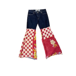 May include: Dark blue denim jeans with patchwork bell bottoms. The patchwork features a red and white checkered pattern on one side and a floral design on the other, creating a unique and stylish look.