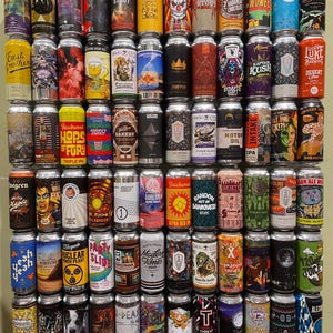 May include: A wall display of colourful aluminium cans of craft beer. The cans are arranged in a grid pattern and feature a variety of designs and labels. Some of the labels include names like "East Brother", "Campfire Stout", "Nor'easter", "Motor Oil", "Random Act of Darkness", "Modern Times", "T-Threat", and "120 Juice".