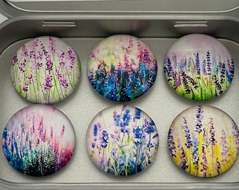 Può includere: Un set di sei magneti rotondi con stampe floreali di lavanda in stile acquerello nei toni del viola, blu e verde, contenuti in una scatola di metallo argentato. L'interno del coperchio mostra il testo Magnet Marketplace e magnetmarketplace.etsy.com.