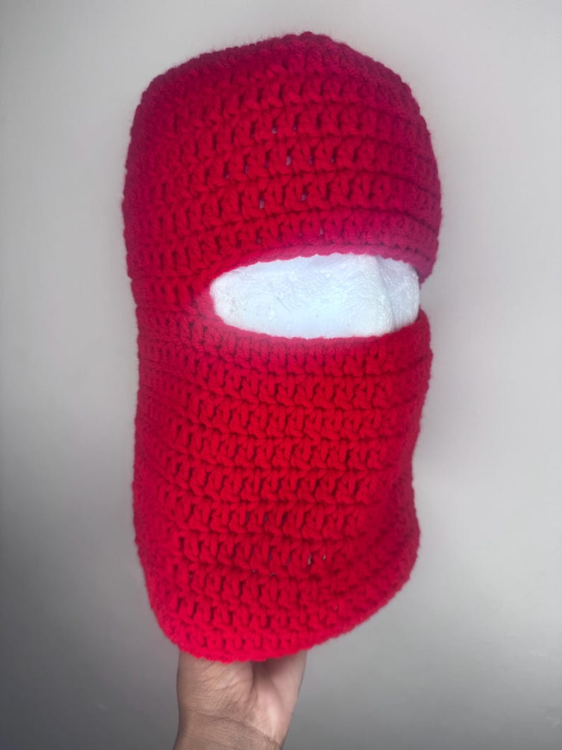 May include: Red crocheted ski mask with a white eye hole opening.
