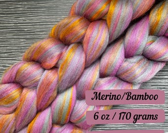 May include: A braid of pink, orange, and gray merino wool and bamboo fiber yarn. The yarn is 6 ounces or 170 grams.