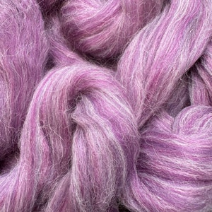 May include: A close-up of a bundle of purple and white wool roving. The wool is soft and fluffy, and it is perfect for spinning or felting.