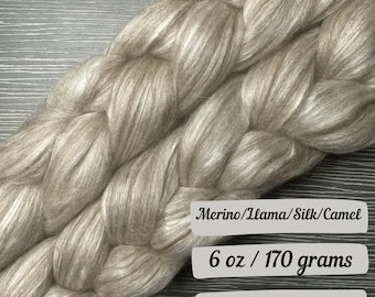 May include: A skein of beige yarn made from a blend of merino wool, llama, silk, and camel fibers. The yarn is 6 ounces or 170 grams.