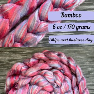Pode incluir: Um pacote de 170 gramas de fibra de bambu rosa, branco e azul. A fibra est&aacute; disposta em um padr&atilde;o tran&ccedil;ado.