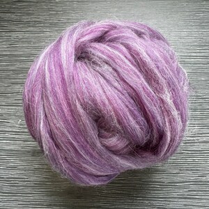 May include: A large ball of purple and white wool yarn. The yarn is soft and fluffy, and it is perfect for knitting or crocheting.