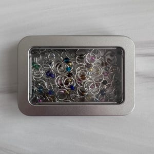 May include: A white ceramic mug with a black handle and the text "But First, Coffee" in a bold, black font. The mug is set against a neutral background, highlighting its simple design.