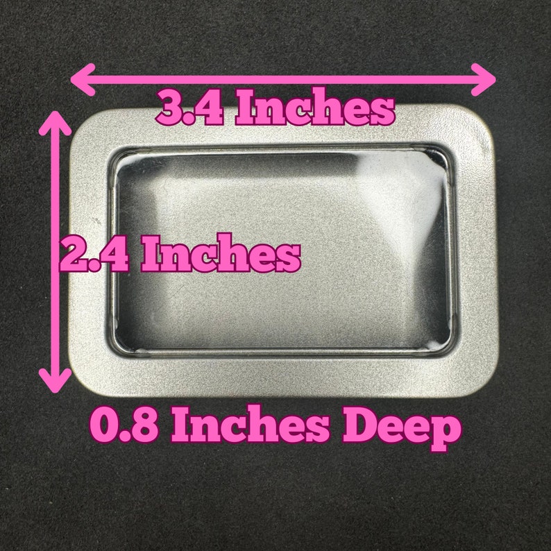 May include: A rectangular silver tin with a clear window. The tin measures 3.4 inches wide, 2.4 inches high, and is 0.8 inches deep. The tin has rounded corners and a shiny finish.