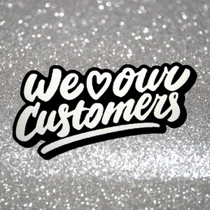 May include: White text on a black background with a heart symbol reads "We &hearts; our customers" against a silver glitter background.