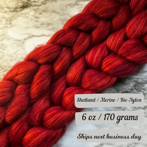 May include: Red, orange, and brown Shetland wool roving with a blend of merino and bio-nylon. The roving is braided and weighs 6 ounces or 170 grams.