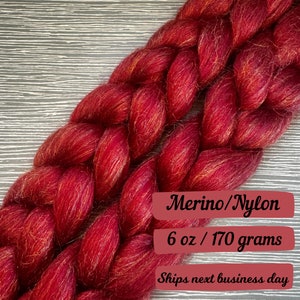 May include: Red merino wool yarn with a subtle gold shimmer, braided and ready for knitting or crocheting. 6 oz / 170 grams.