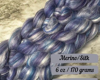May include: A skein of blue, white, and purple merino wool yarn blended with silk. The yarn is 6 ounces or 170 grams. Merino/Silk. Ships next business day.