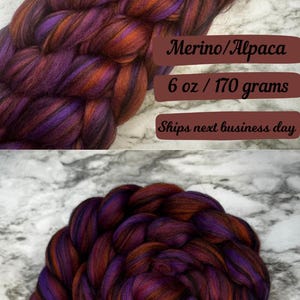 May include: Close-up of Merino/Alpaca fiber in shades of purple, orange, and brown. The fiber is shown in various forms, including a braid and a coiled bundle. The text on the image reads "6 oz / 170 grams".