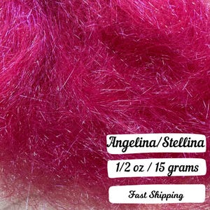 May include: Close-up of a vibrant magenta fiber material, possibly for crafting or embellishment. The text "Angelina/Stellina" is displayed, along with "1/2 oz / 15 grams". The fibers have a shimmering, metallic quality.