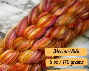 May include: A braid of orange, yellow, pink, and white merino wool and silk yarn. The yarn is 6 ounces or 170 grams.