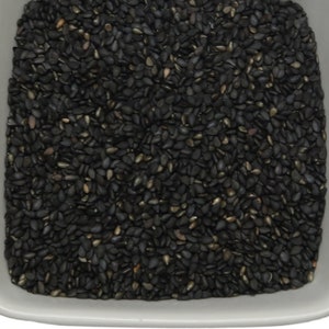 May include: A white ceramic bowl filled with black sesame seeds.