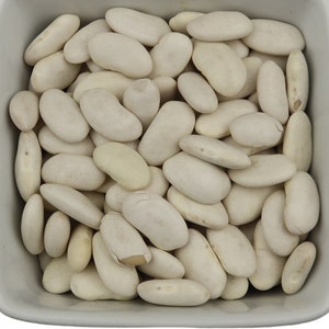 Puede incluir: Un tazón blanco lleno de frijoles blancos secos.