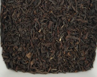 May include: A white ceramic bowl filled with loose black tea leaves.