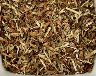 May include: A square white bowl filled with dried herbs. The herbs are a mix of brown, green, and tan, with a variety of textures. The bowl is set against a white background, highlighting the natural colors of the herbs.