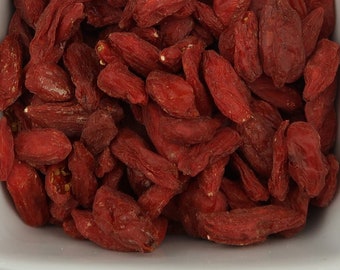 May include: A white bowl filled with dried goji berries. The berries are a deep red colour and have a wrinkled texture.