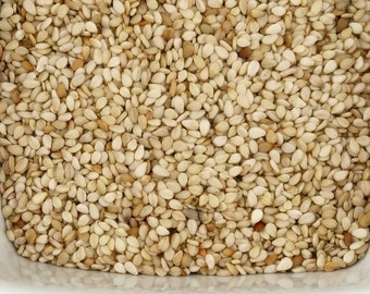 May include: A white ceramic bowl filled with raw, unhulled sesame seeds.