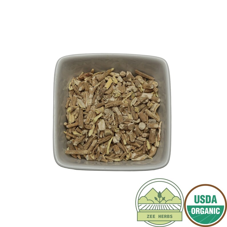 May include: A white ceramic bowl filled with dried, light brown and beige pieces of organic angelica root. The bowl is on a white background. The image also includes a green and white USDA Organic seal and a green and white Zee Herbs logo.