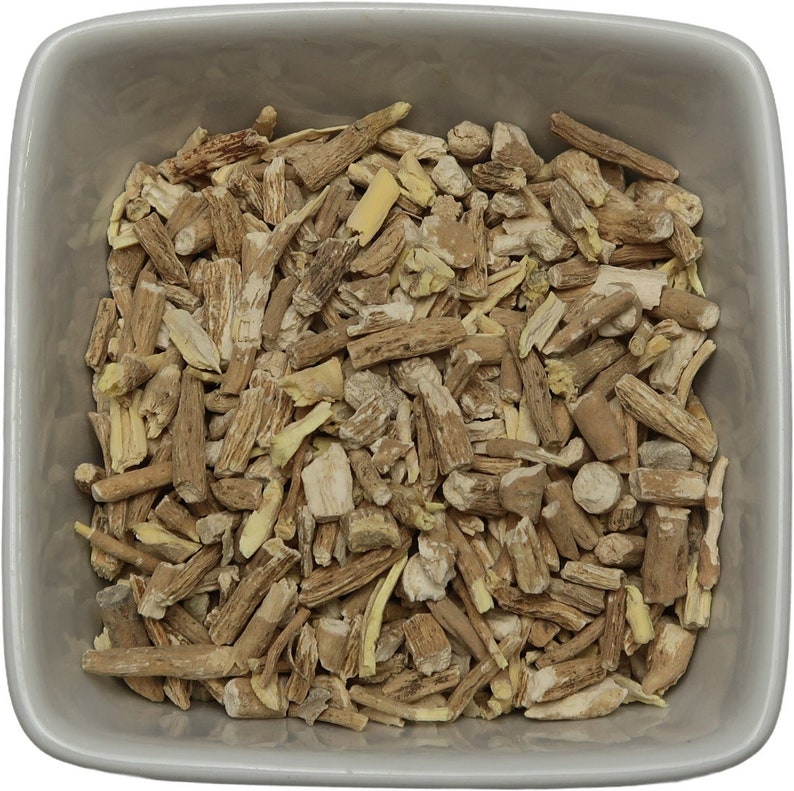 May include: A close-up view of a bowl filled with dried, light brown and beige root pieces. The pieces are irregularly shaped and have a rough texture.