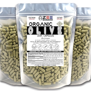 May include: Two clear plastic bags filled with green capsules labeled "ORGANIC OLIVE LEAF, CAPSULES Olea Europaea" and "NUTRIENT-DENSE HERBAL POWDER RICH IN ANTIOXIDANTS & POLYPHENOLS NATURALLY SUPPORTS OVERALL WELLNESS" with the brand name "ZEE HERBS" printed on the bags.
