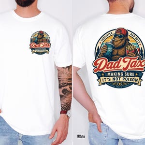 Puede incluir: Camiseta blanca con un gr&aacute;fico colorido en la parte delantera y trasera. El gr&aacute;fico frontal presenta un personaje parecido a Bigfoot con el texto "Dad Tax". El gr&aacute;fico trasero incluye el texto "Dad Tax - Making Sure It's Not Poison".