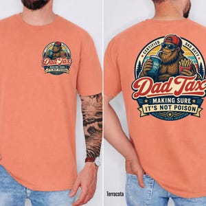 Puede incluir: Camiseta de color terracota con un gr&aacute;fico en la parte delantera y trasera. El gr&aacute;fico frontal dice "Dad Tax" con un Bigfoot de dibujos animados. El gr&aacute;fico trasero presenta el mismo Bigfoot con el texto "Dad Tax, Making Sure It's Not Poison, Official Snack Inspector."