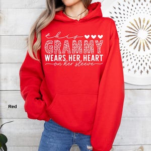 May include: A red hooded sweatshirt with the text "this Grammy wears her heart on her sleeve" in white script and a leopard print design. The sweatshirt has a front pocket and a drawstring hood.