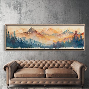 Op de afbeelding: Een aquarel schilderij van een bergketen met een bos op de voorgrond. De bergen zijn geschilderd in tinten oranje, geel en rood, terwijl het bos is geschilderd in tinten blauw en groen. Het schilderij is ingelijst in een houten lijst.