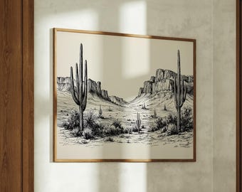 May include: A framed black and white desert landscape print featuring saguaro cacti and a mountain range. The artwork is displayed above a wooden dresser in a room with a wooden chair and a window.