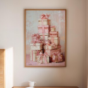 May include: A framed artwork depicts a stack of gift boxes in shades of pink and white, tied with pink ribbons. The painting hangs above a wooden nightstand with two drawers. A book and a mug sit on the nightstand.