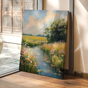 May include: A painting of a river flowing through a field of wildflowers. The sky is blue with white clouds. The painting is framed and hanging on a wall.